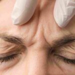 An aesthetic provider performing a detailed facial evaluation for a Daxxify treatment in Coral Gables