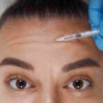 A medical provider conducting a precise facial assessment for forehead Botox injections in a Coral Gables clinic.