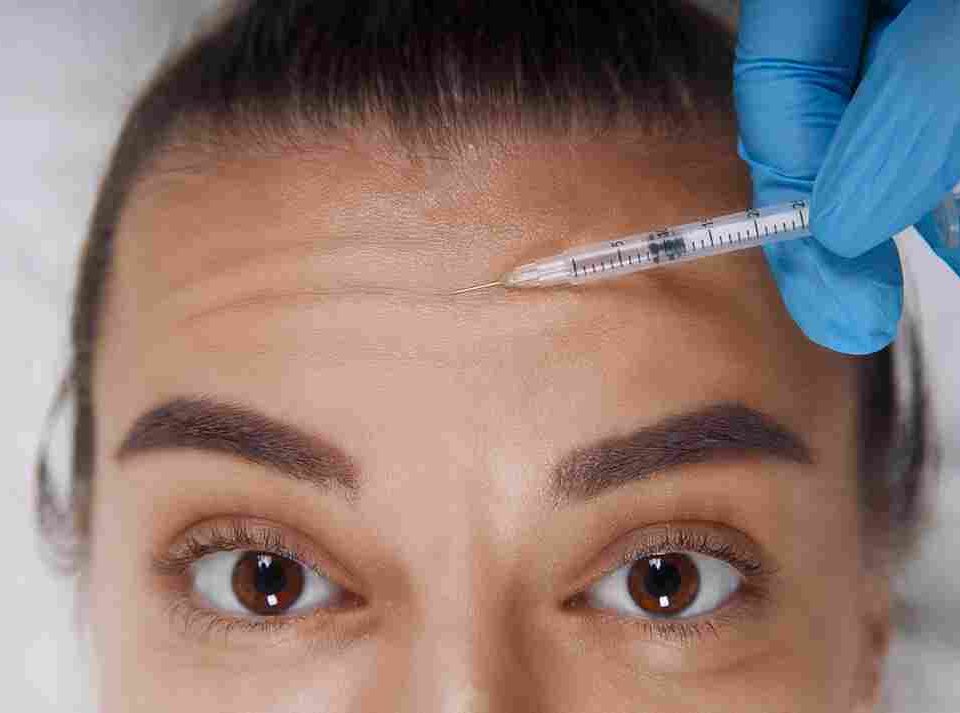 A medical provider conducting a precise facial assessment for forehead Botox injections in a Coral Gables clinic.